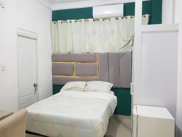 A bedroom with a bed, a white wardrobe, and a white cabinet.