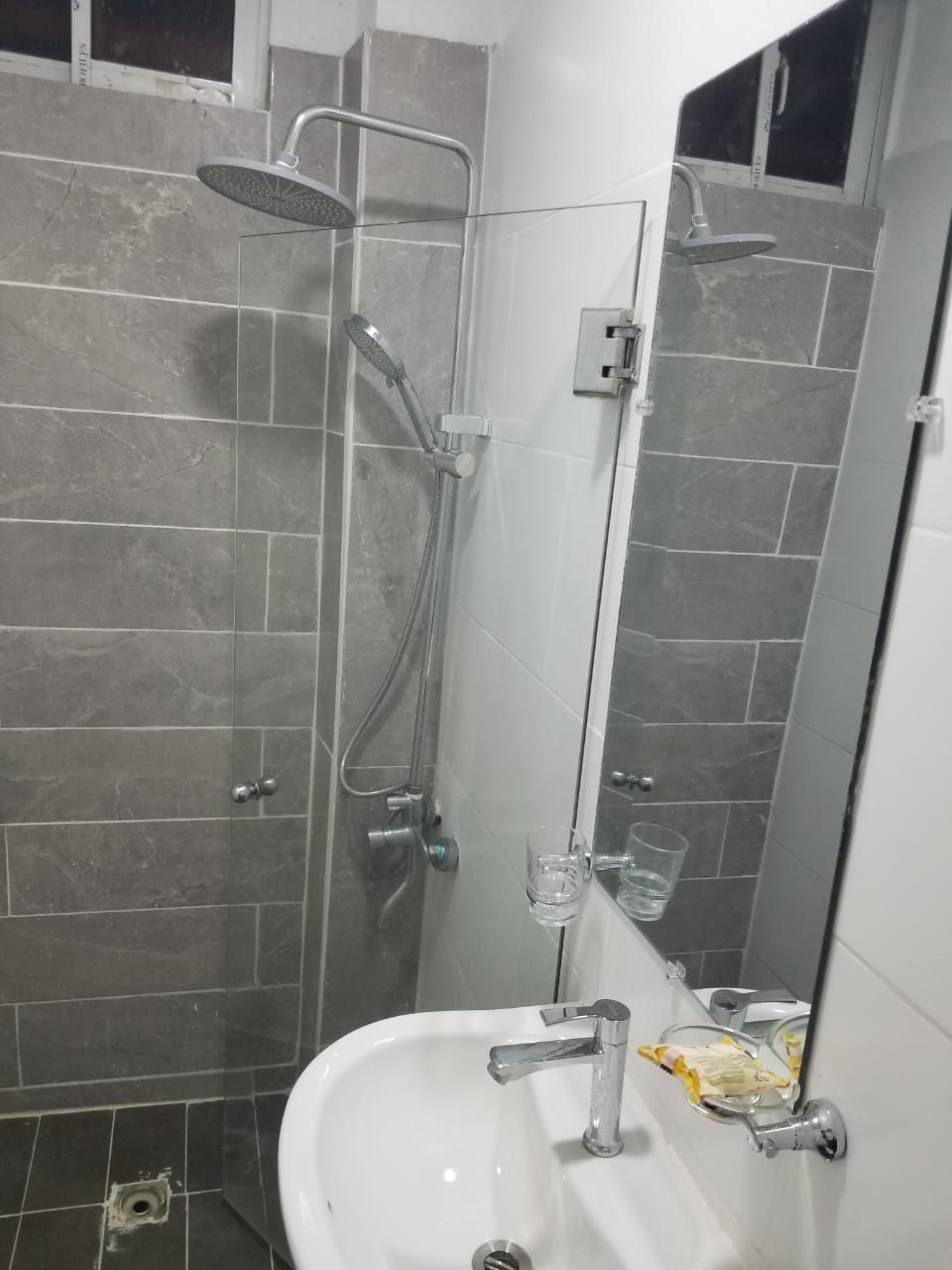 Ein Badezimmer mit Dusche, Waschbecken und Spiegel.