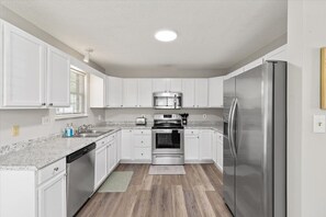 A modern kitchen with white cabinets, stainless steel appliances, and a granite countertop.