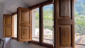 A room with a large window, wooden shutters, and a view of a mountainous landscape. - Bright Village apartment, wrap around mountain views in Fornalutx.HighspeedWIFI (fornalutx)
