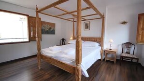 A four-poster bed in a room with wooden flooring, a small bedside table with a lamp, and a chair. - Bright Village apartment, wrap around mountain views in Fornalutx.HighspeedWIFI (fornalutx)