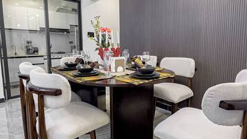 A modern dining area with a round table, white cushioned chairs, and a decorative centerpiece.