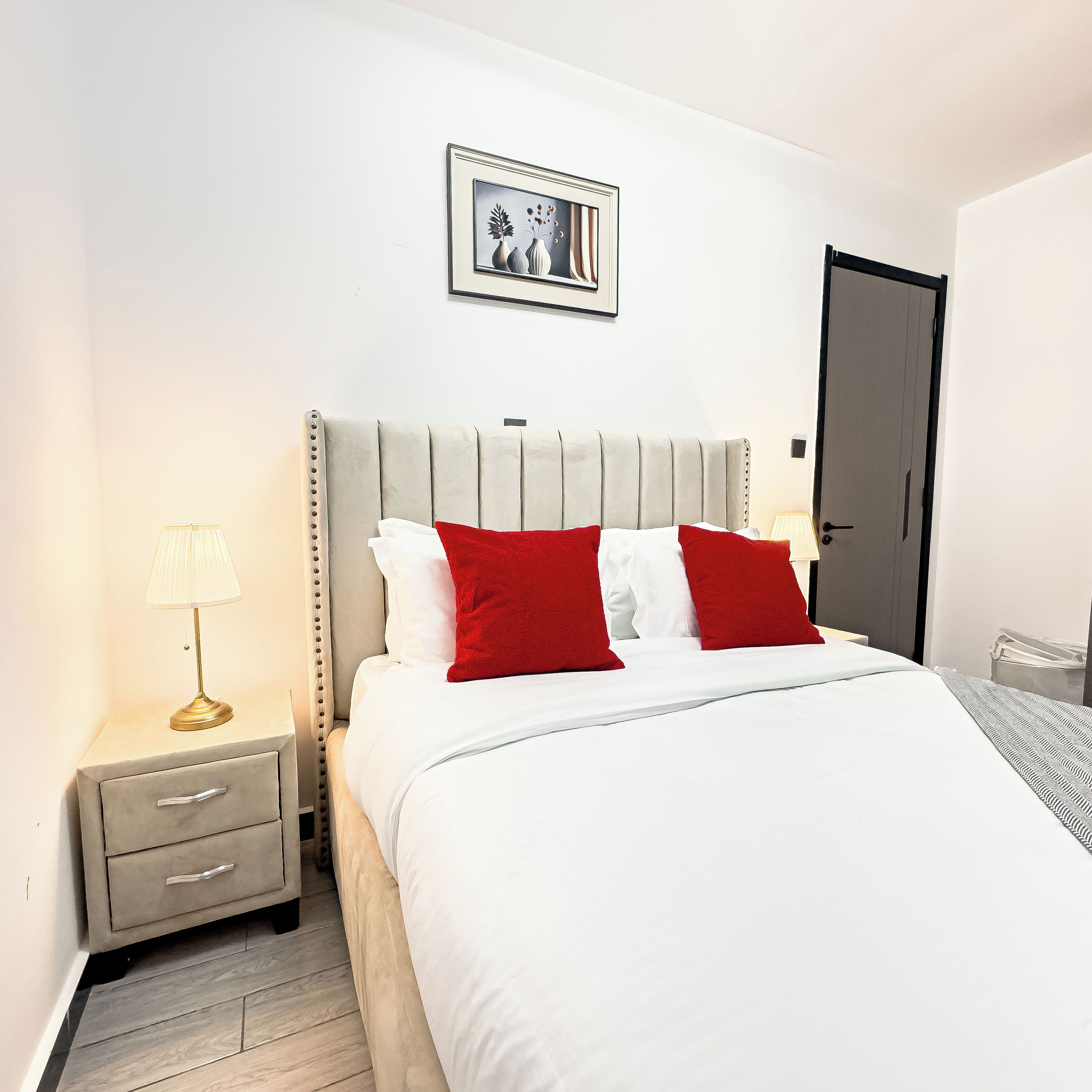 Ein Hotelzimmer mit einem Bett, einem Nachttisch, einer Lampe und einer Tür.