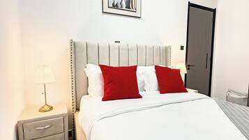 Ein Hotelzimmer mit einem Bett, einem Nachttisch, einer Lampe und einer Tür.