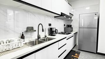 A modern kitchen with white cabinets, stainless steel appliances, and a black countertop.