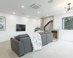 Ein modernes Wohnzimmer mit einer Couch, einem Kamin und einem an der Wand befestigten Fernseher.