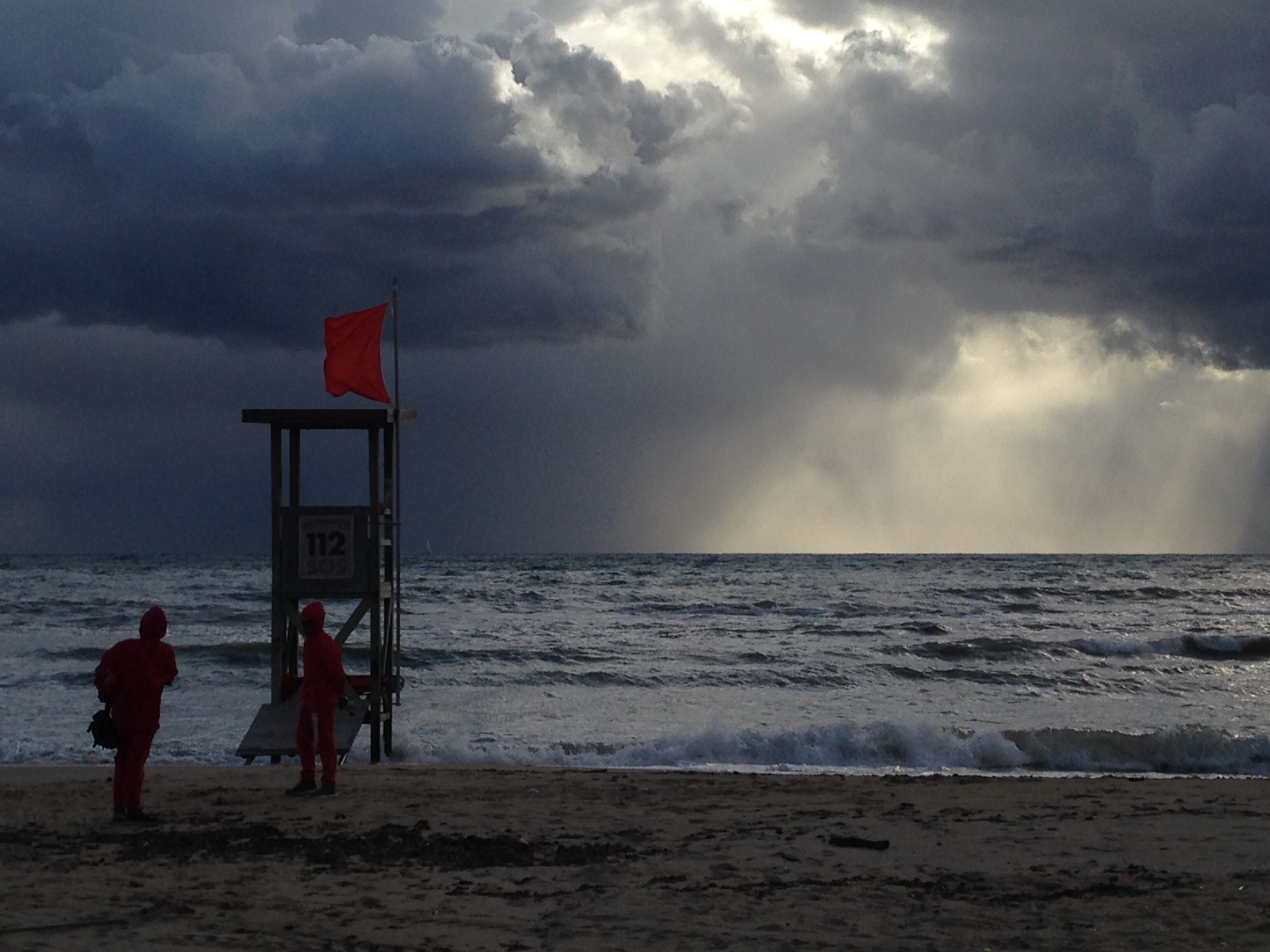 Torre de socorristes amb una bandera a la platja, amb onades.