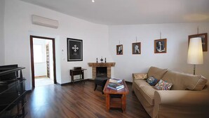 Ein Wohnzimmer mit einer Couch, einem Couchtisch, einem Kamin und gerahmten Bildern an der Wand.