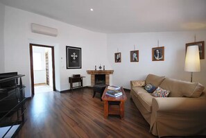 A living room with a sofa, a coffee table, a fireplace, and framed pictures on the wall. - Spacious 70M duplex apartment, panoramic views in mountain village of Fornalutx (fornalutx)