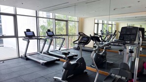 A gym with treadmills, exercise bikes, and a mirrored wall. - Stylish Studio in DAMAC Hills with Pool, Gym & Balcony (Damac hills)