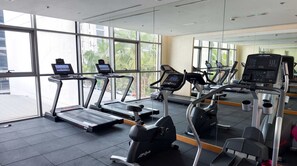 A gym with treadmills, exercise bikes, and a mirrored wall. - Stylish Studio in DAMAC Hills with Pool, Gym & Balcony (Damac hills)