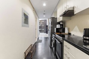 A modern kitchen with stainless steel appliances, a coffee maker, and a toaster. - Stylish Studio in DAMAC Hills with Pool, Gym & Balcony (Damac hills)