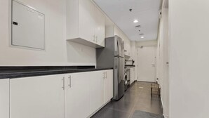 A modern kitchen with white cabinets, a stainless steel refrigerator, and a built-in oven. - Stylish Studio in DAMAC Hills with Pool, Gym & Balcony (Damac hills)