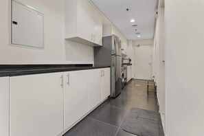 A modern kitchen with white cabinets, a stainless steel refrigerator, and a built-in oven. - Stylish Studio in DAMAC Hills with Pool, Gym & Balcony (Damac hills)