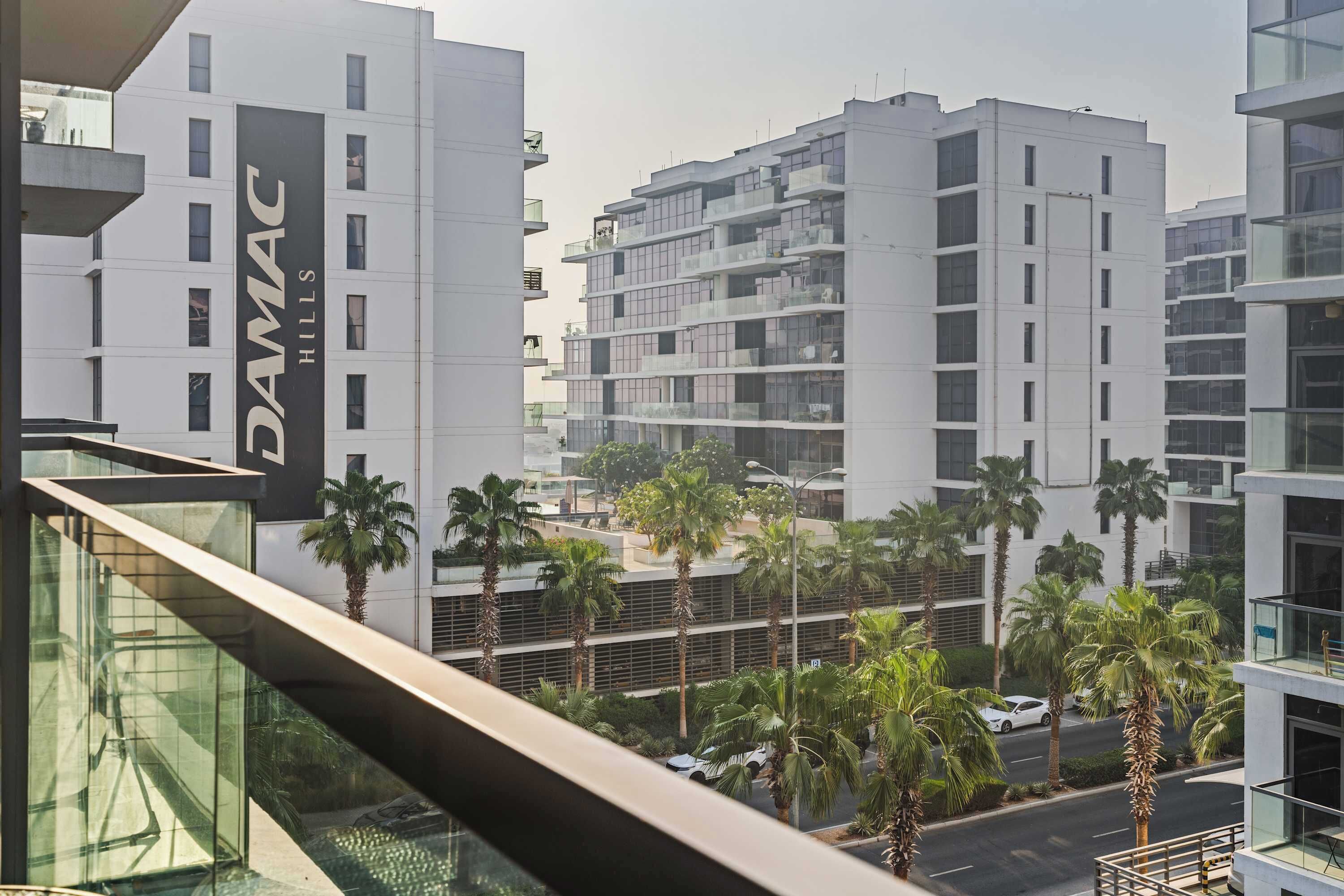 A modern building with a prominent sign reading 'DAMAC HILLS'.