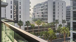 A modern building with a prominent sign reading 'DAMAC HILLS'. - Stylish Studio in DAMAC Hills with Pool, Gym & Balcony (Damac hills)
