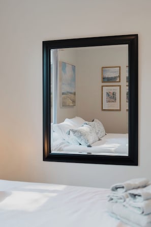 A hotel room with a bed, a mirror, and artwork on the wall. - Beach Retreat - Hot Tub - 10 min Walk to Bay Beach (Fort Erie)