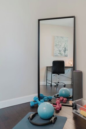 A home gym with exercise equipment, a large mirror, and a chair. - Beach Retreat - Hot Tub - 10 min Walk to Bay Beach (Fort Erie)