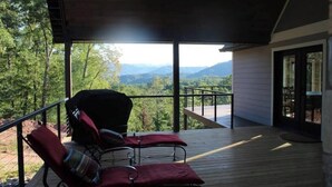 Un espace extérieur abrité, aménagé avec deux chaises et offrant une vue sur un paysage montagneux.