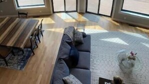 Une pièce avec un plafond en pente, de grandes fenêtres, un canapé et une table à manger.