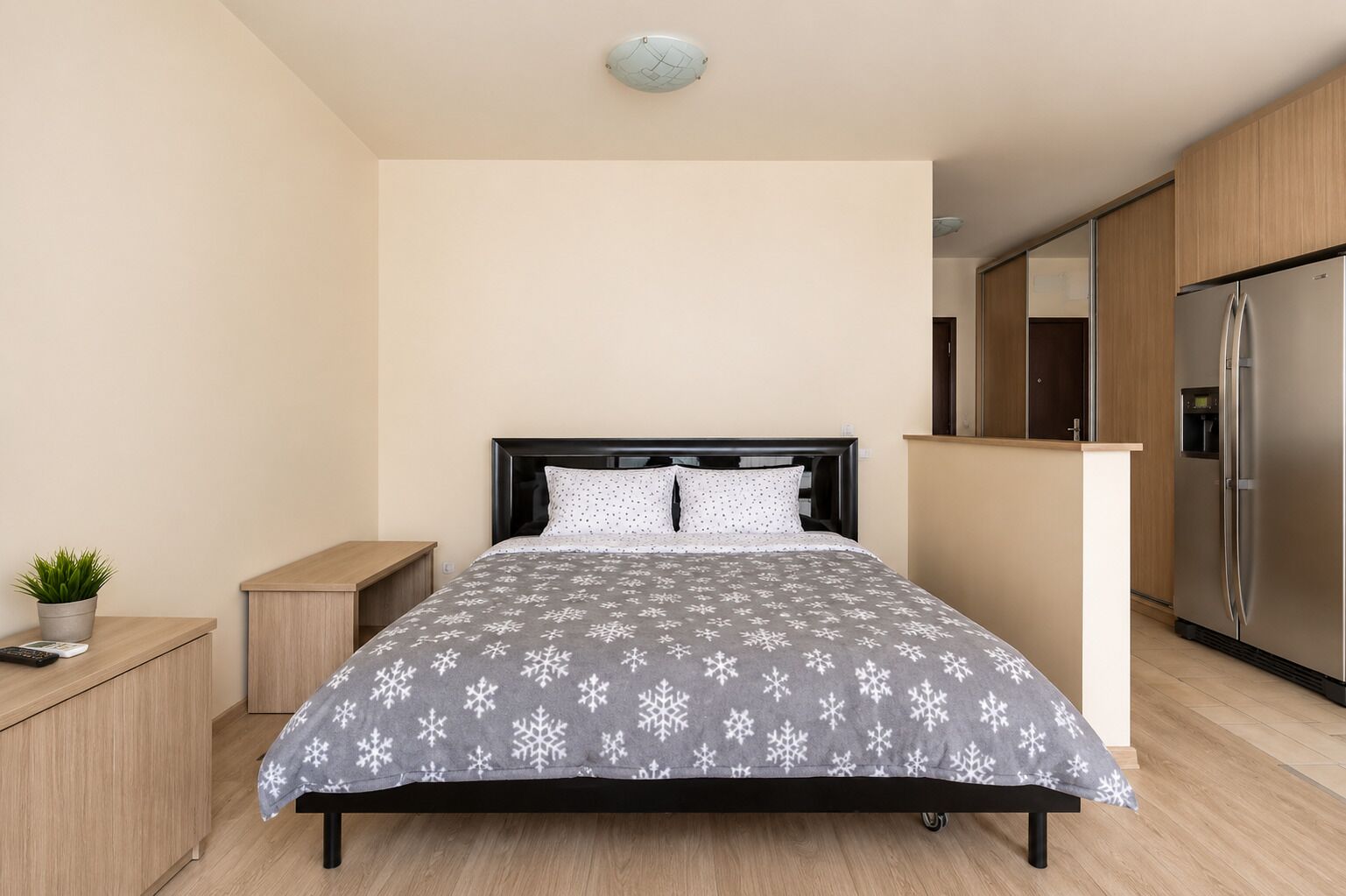 A modern bedroom with a bed, bedside table, and a small potted plant.