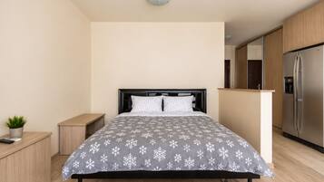 A modern bedroom with a bed, bedside table, and a small potted plant.