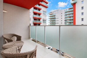 A balcony with wicker furniture and a view of multi-story buildings with balconies. - City Oasis Studio in Oradea with Balcony • Fast WiFi • Self Check-in • AC (Oradea)