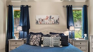 Een slaapkamer met een groot bed, twee nachtkastjes, een hoofdeinde en een raam met gordijnen.