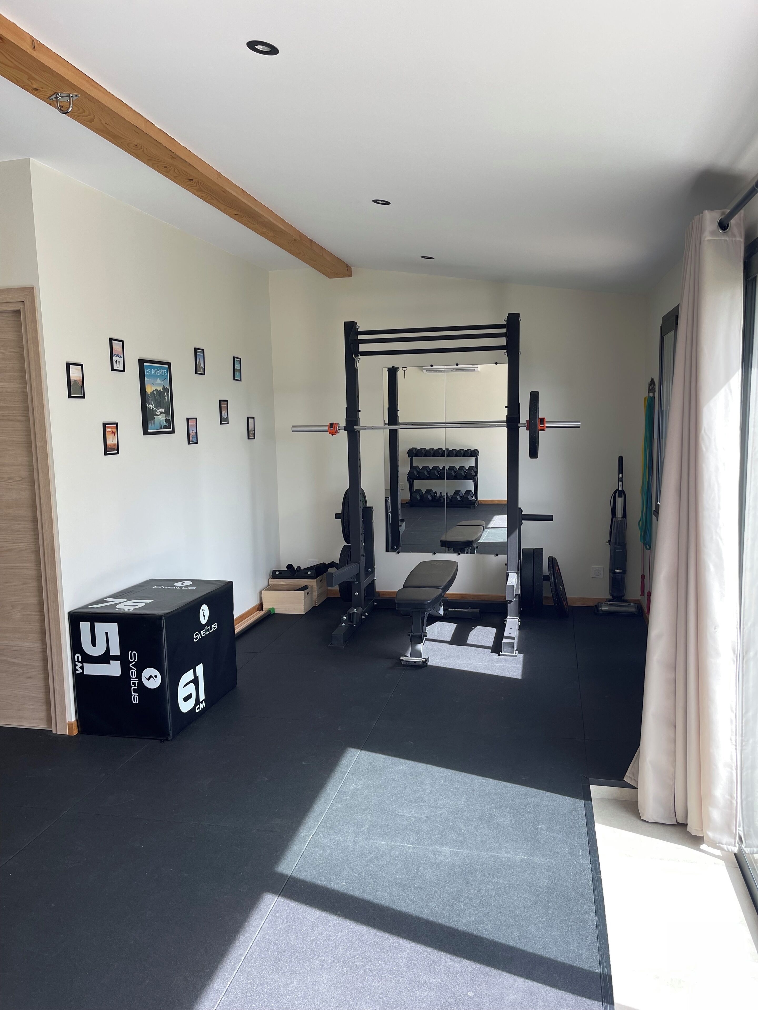 A gym with a squat rack, bench, and weight storage.