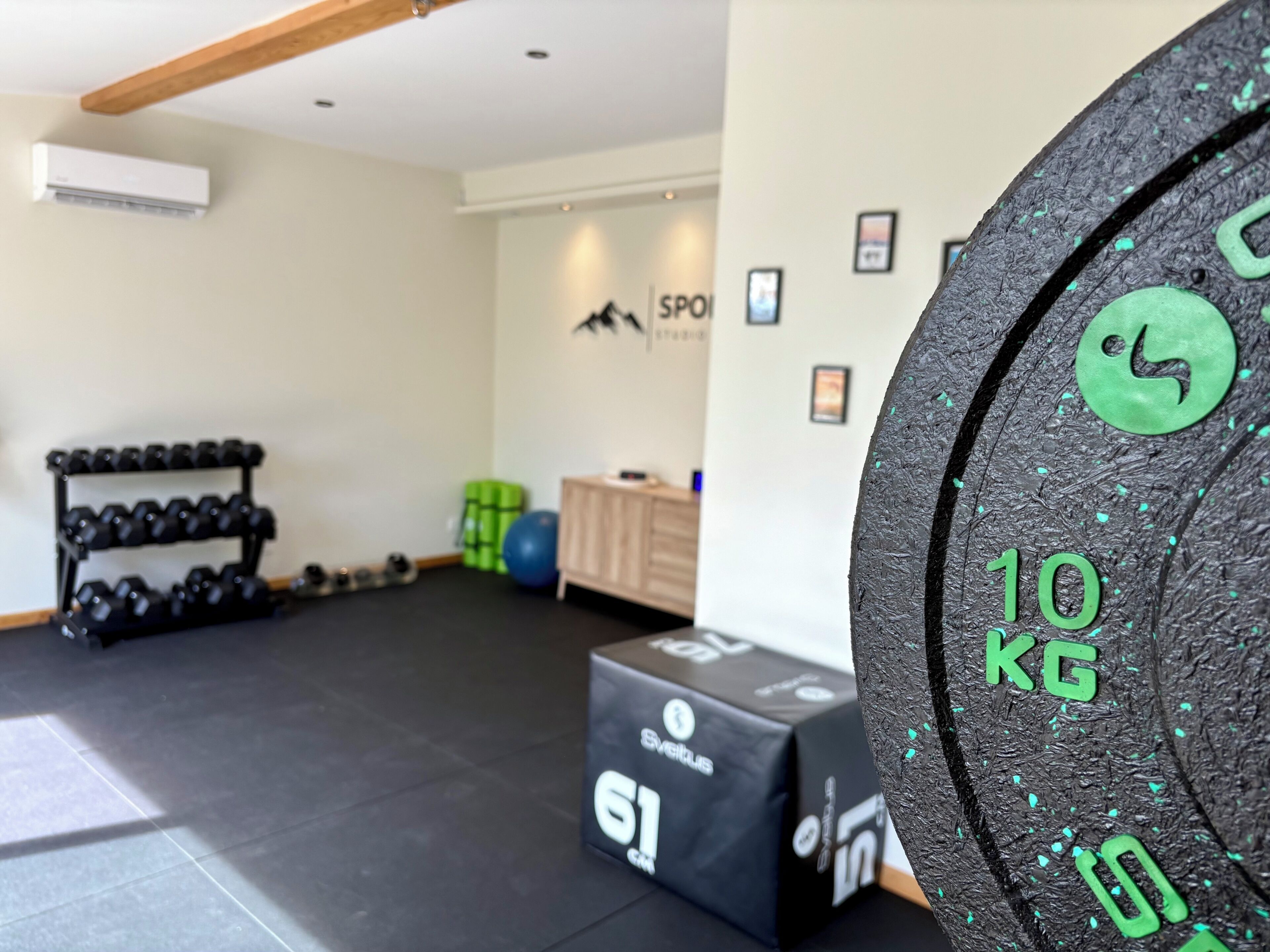 Ein Fitnessstudio mit einer Hantelbank, Kurzhanteln und Trainingsbällen.