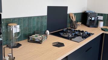 Una cocina moderna con estufa a gas, máquina de café y campana extractora.