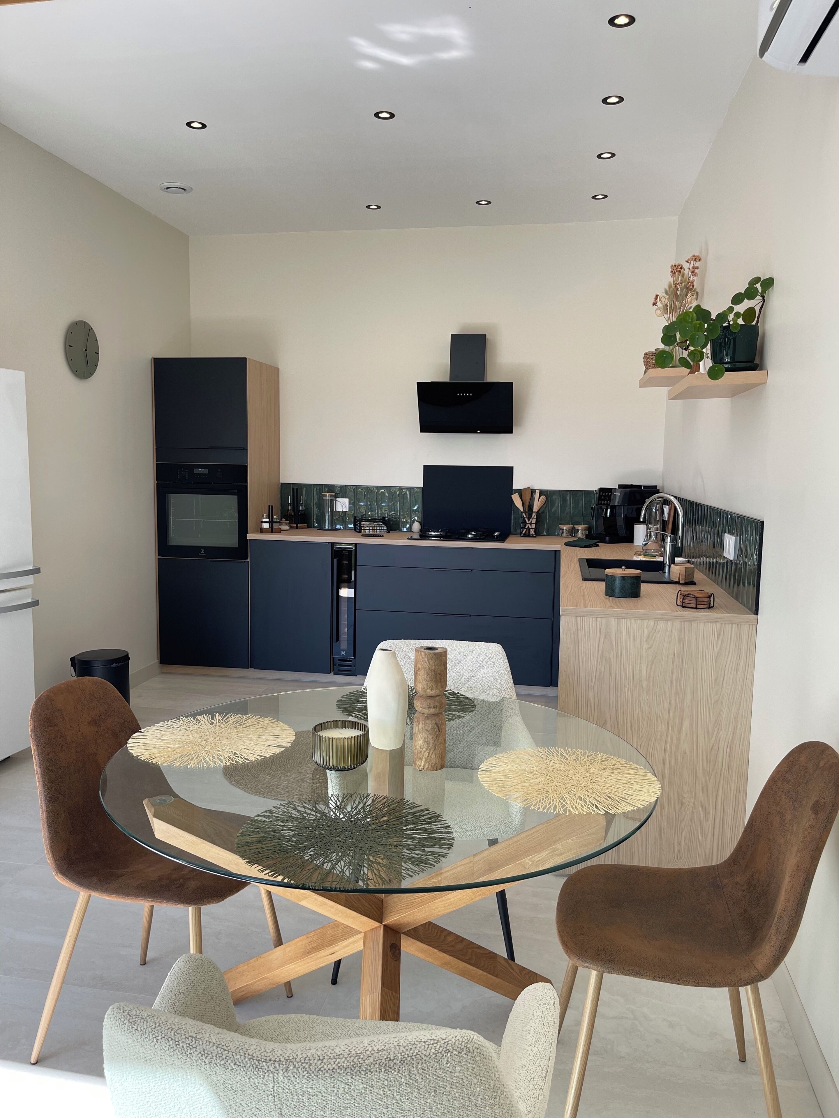 A modern kitchen with a central island, built-in appliances, and a dining area with a glass table and cushioned chairs.