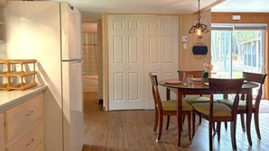 A kitchen with wooden cabinets, a white refrigerator, a dining table with chairs, and a door leading to a balcony.
