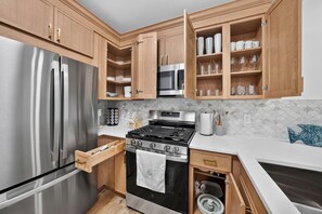 Una cocina con un refrigerador de acero inoxidable, un microondas, una estufa y gabinetes de madera.