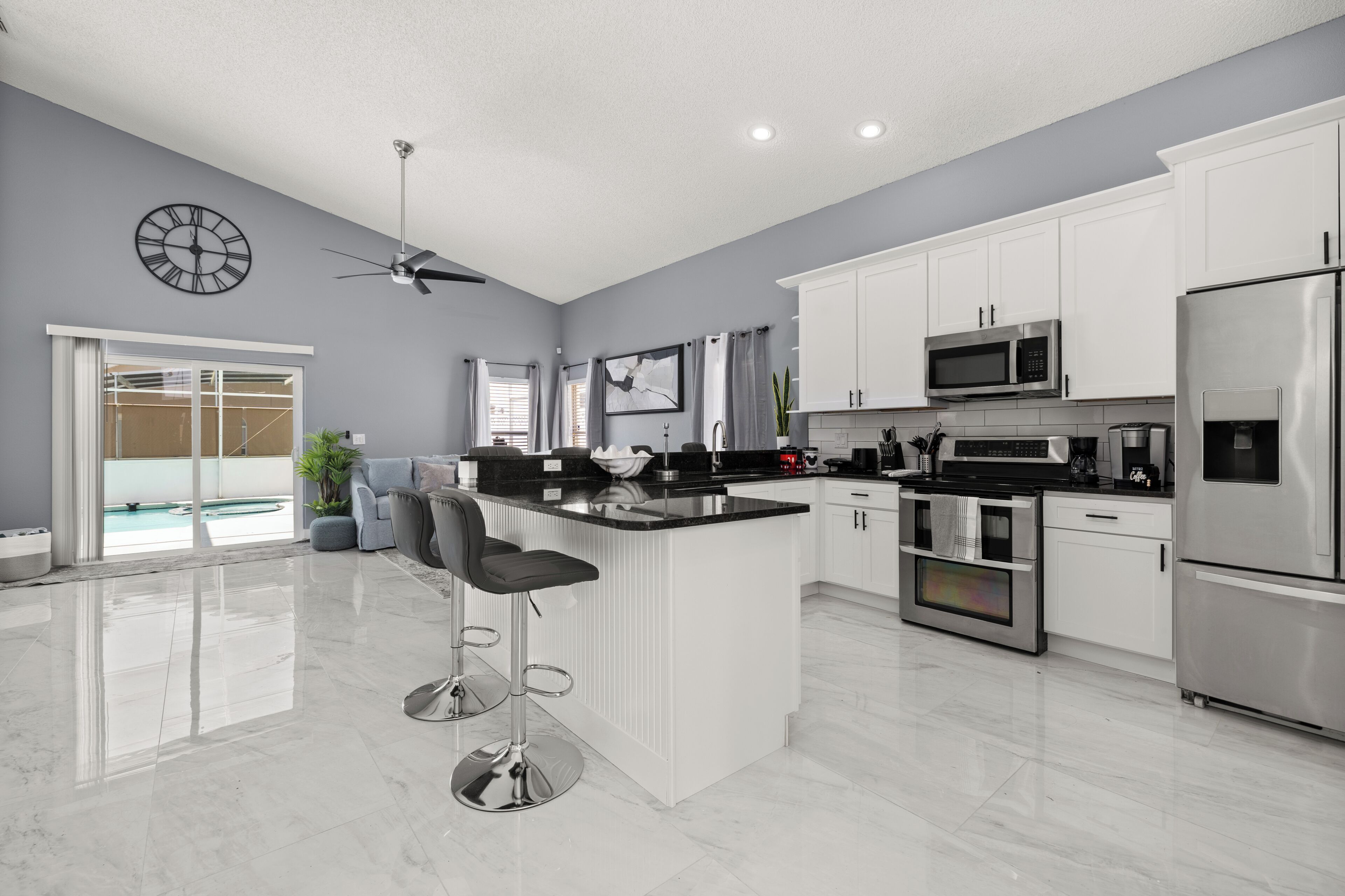 A modern kitchen with white cabinets, stainless steel appliances, and a central island with bar stools.