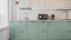 A kitchen with teal cabinets, a microwave, and a coffee maker. - ZU12/4 Spacious and bright apartment in Milan (Milano)