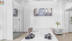 A modern bedroom with a bed, a glass shower enclosure, a white bedside table with a vase of flowers, and a wall-mounted artwork. - ZU12/4 Spacious and bright apartment in Milan (Milano)