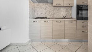 A modern kitchen with a gas stove, a built-in oven, and wooden cabinetry. - ZAN20: A Comfortable and Bright Apartment in Milan (Milano)