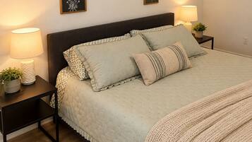 Een slaapkamer met een bed, twee nachtkastjes, een vloerkleed en kunst aan de muur.