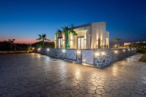 A modern building with a stone facade, large windows, and a paved courtyard. - Seaside Villa with Heated Pool, By Hellocrete (Pigianos Kampos)