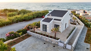 Ein modernes Haus mit Mauerwerk, einem gepflasterten Zugang und Blick aufs Meer.