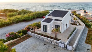 A modern house with a stone wall, a paved driveway, and a view of the sea. - Seaside Villa with Heated Pool, By Hellocrete (Pigianos Kampos)