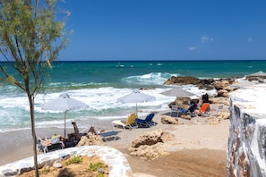 A beach with rocky terrain, umbrellas, and beach chairs. - Seaside Villa with Heated Pool, By Hellocrete (Pigianos Kampos)