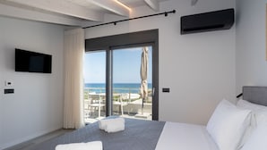 Ein Hotelzimmer mit Bett, Fernseher, Meerblick und einem Balkon mit Sitzgelegenheit.