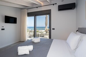 A hotel room with a bed, a TV, a view of the sea, and a balcony with outdoor seating. - Seaside Villa with Heated Pool, By Hellocrete (Pigianos Kampos)