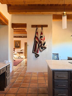 A kitchen with a stone-tiled floor, wooden cabinets, and a hanging towel.