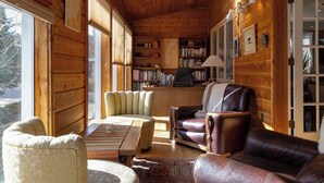 Een gezellig houten interieur met een open haard, een boekenkast en lederen meubels.