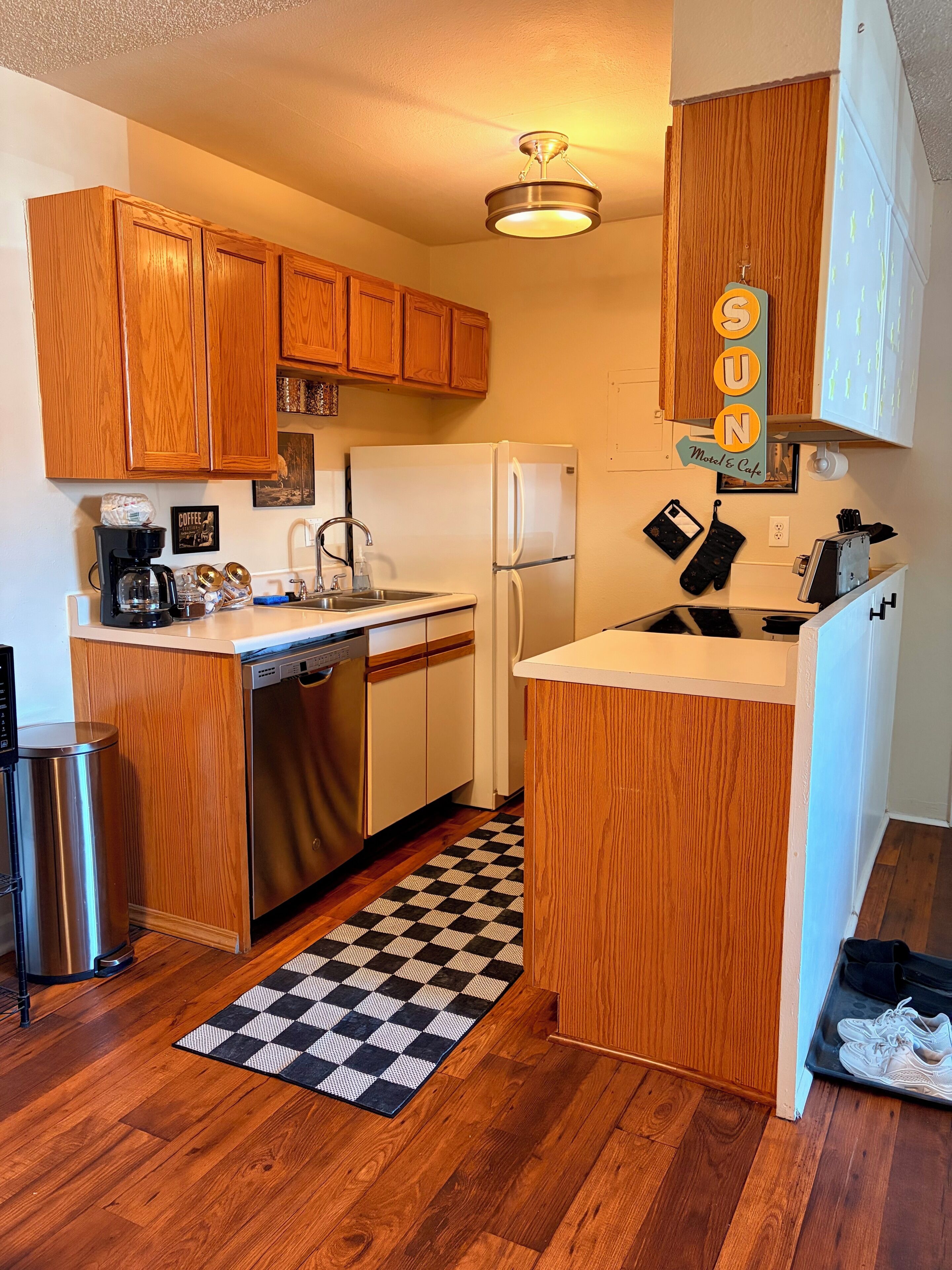 A compact kitchen with wooden cabinets, a white refrigerator, a coffee maker, and a microwave.