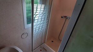 Un bagno con doccia, un water e una finestra con vista sul verde circostante.