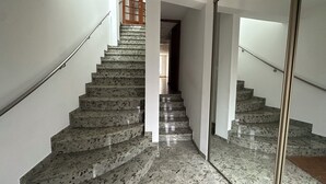 A staircase with a handrail, leading to a landing with a door. - Village house nestled among ponds, scrubland, and a wild beach (La Palme)